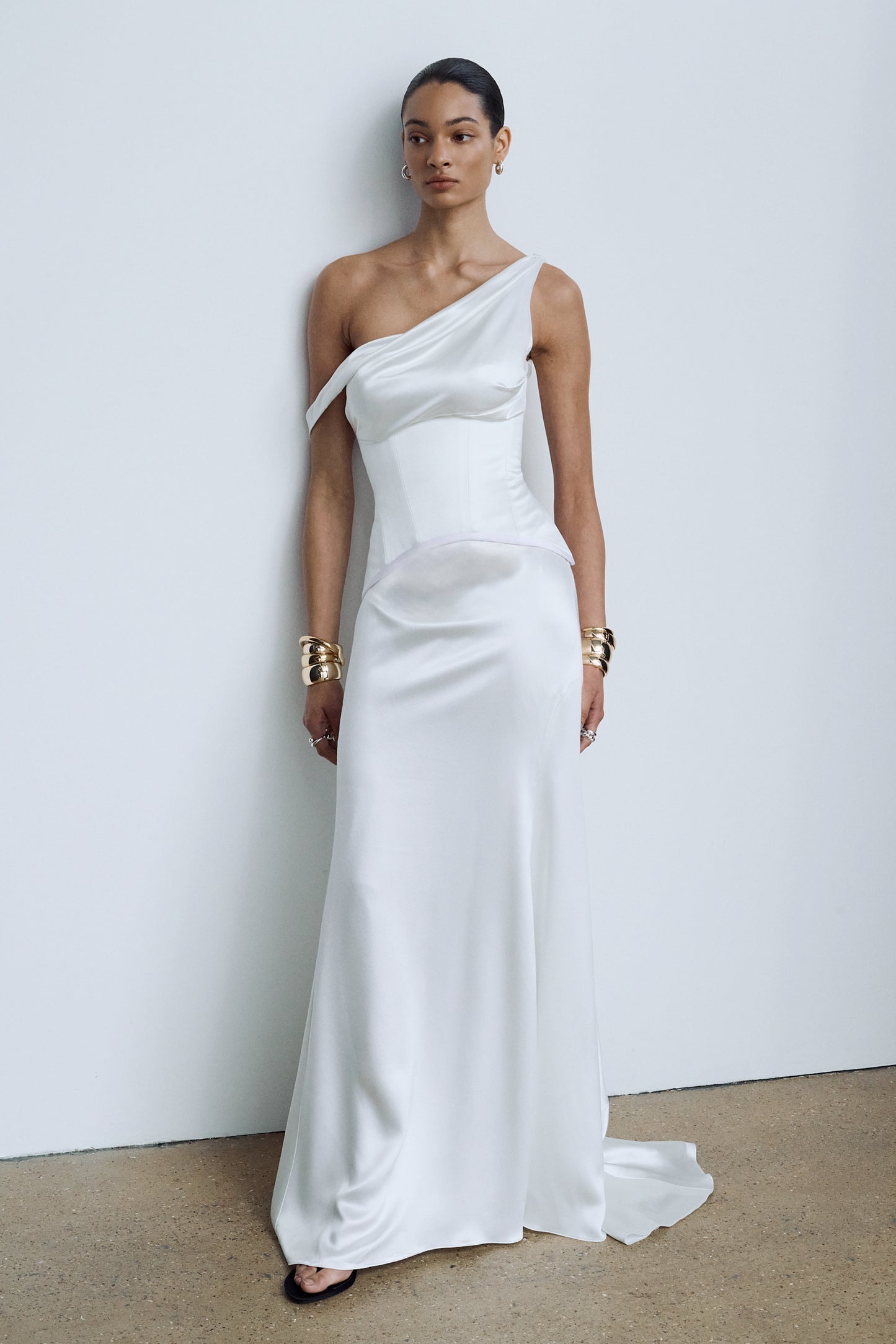 Minimalist white asymmetric wedding gown, styled with a sculptural waspie corset