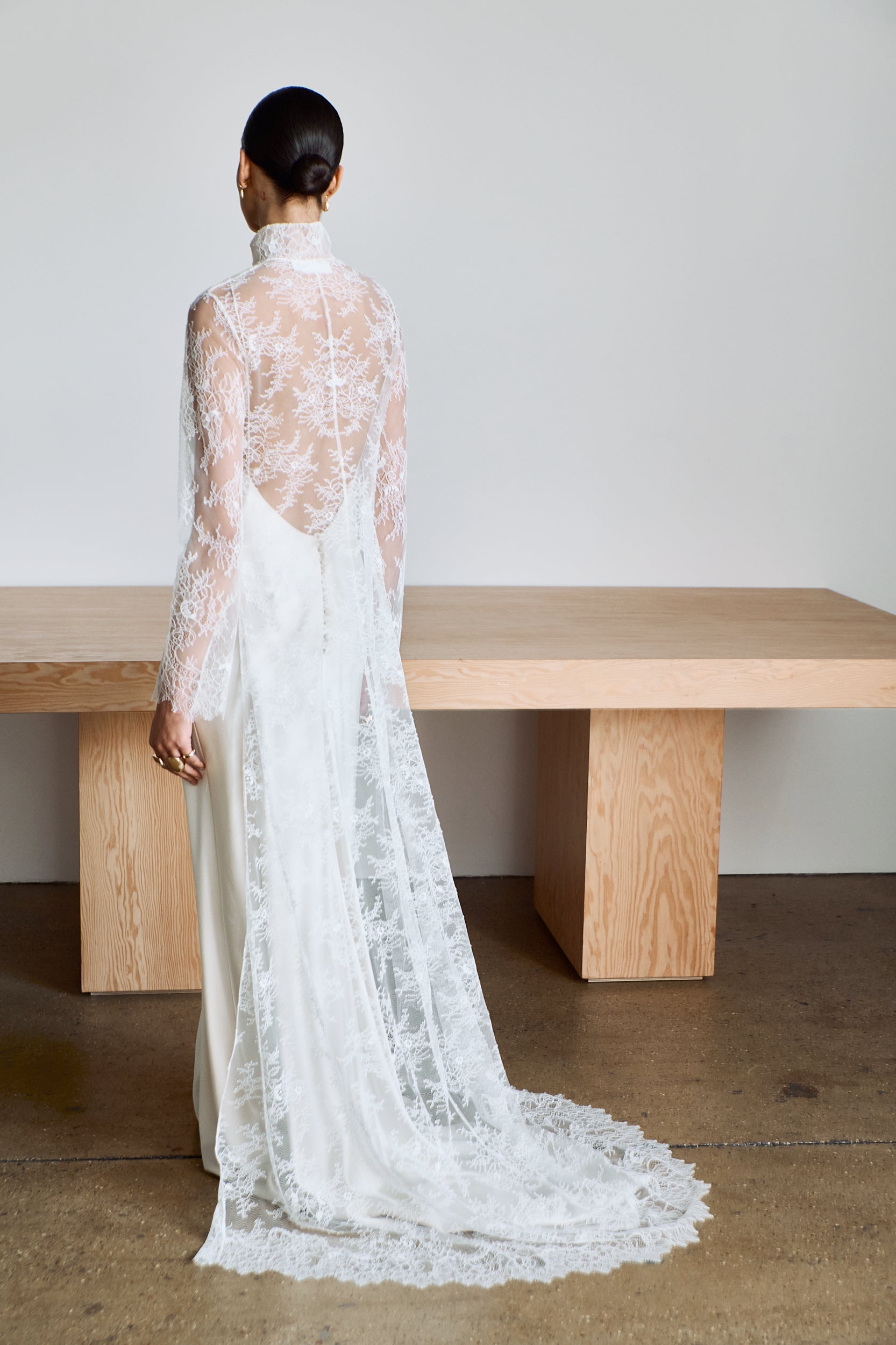 Person wearing a long, sheer lace cape with long sleeves and a high neckline.