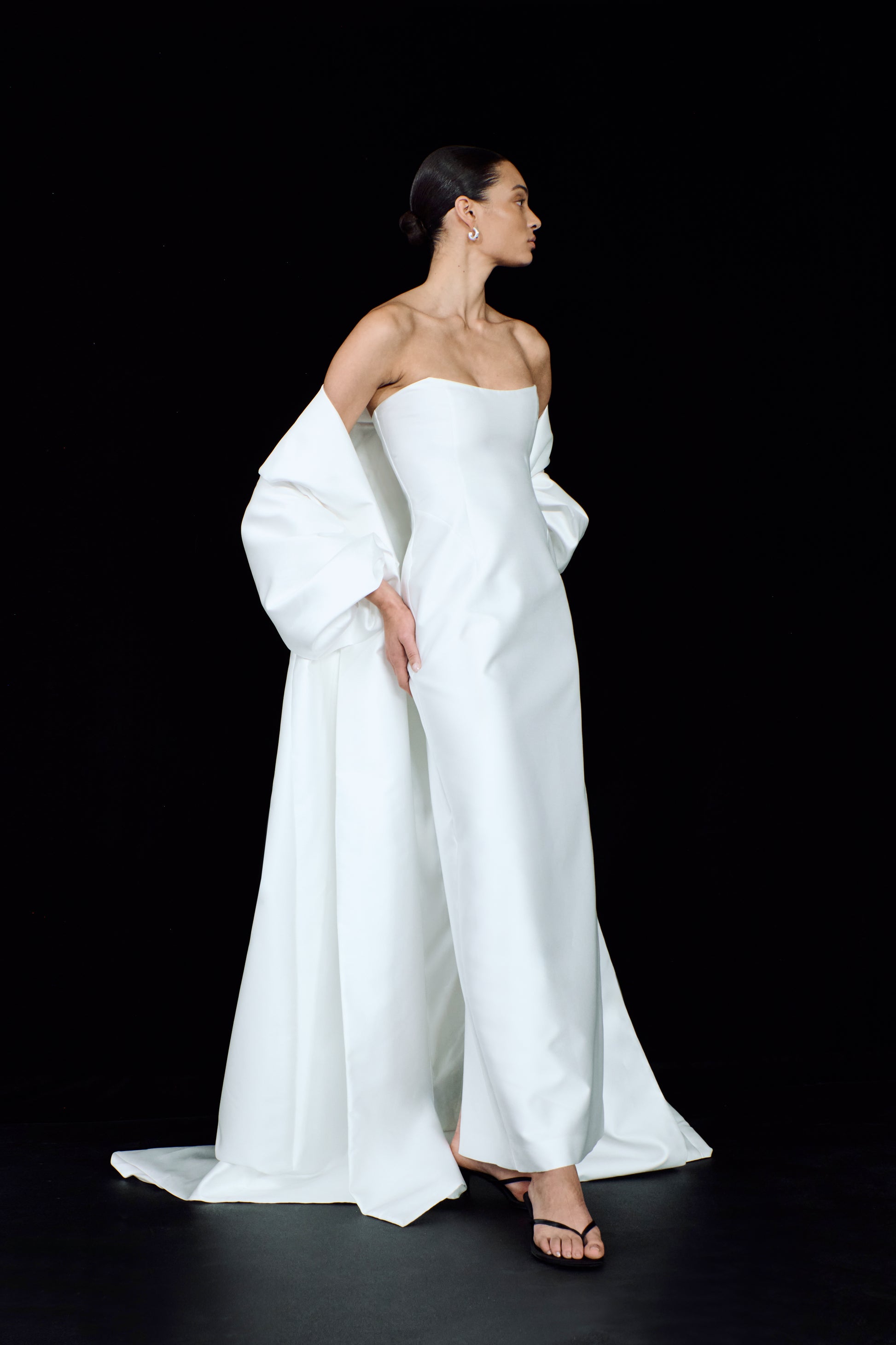 An elegant mikado strapless bridal gown, styled with a dramatic, flowing opera cloak.