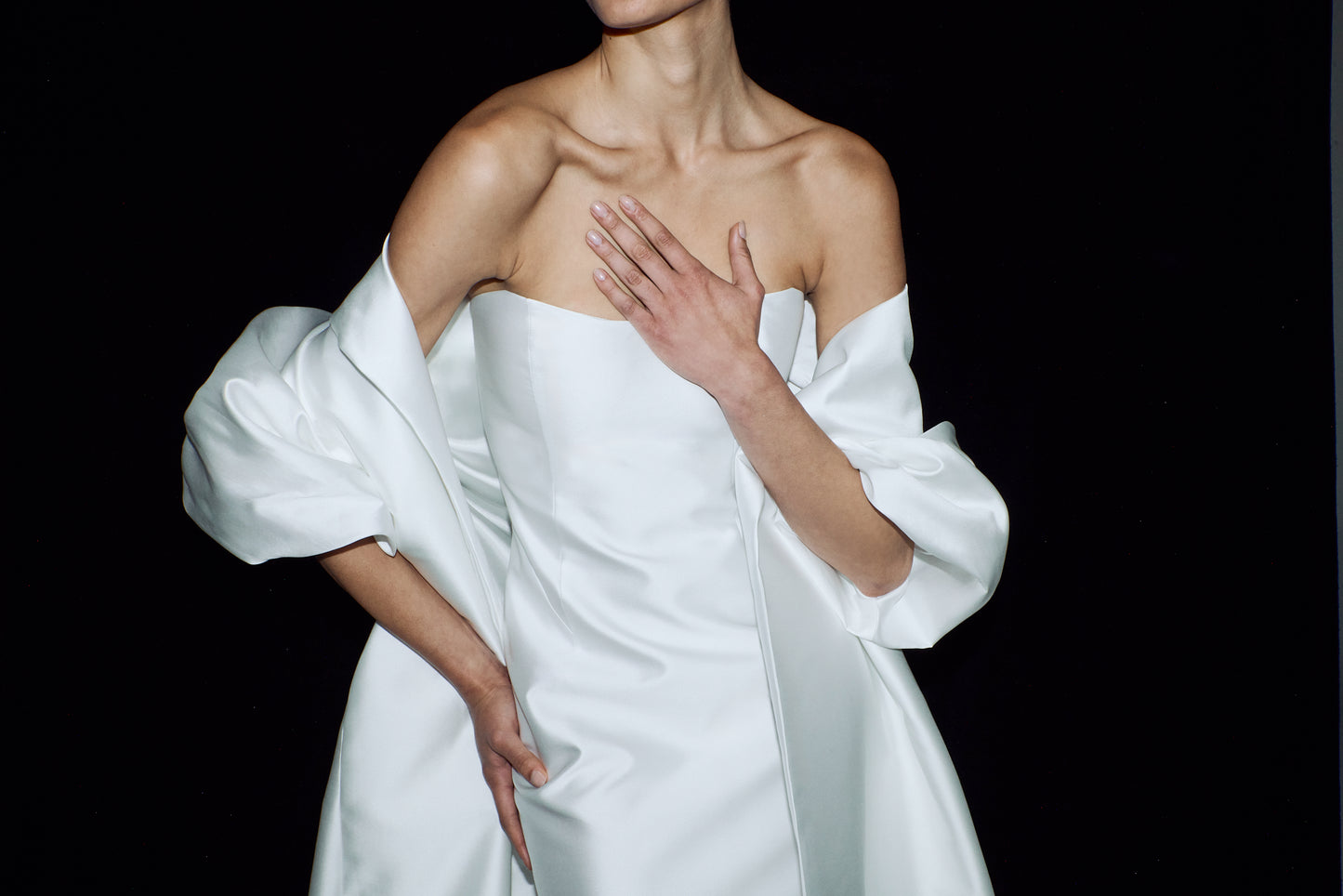 Close-up showing the elegant strapless neckline and draped detailing of a column wedding gown styled with an opera cloak.