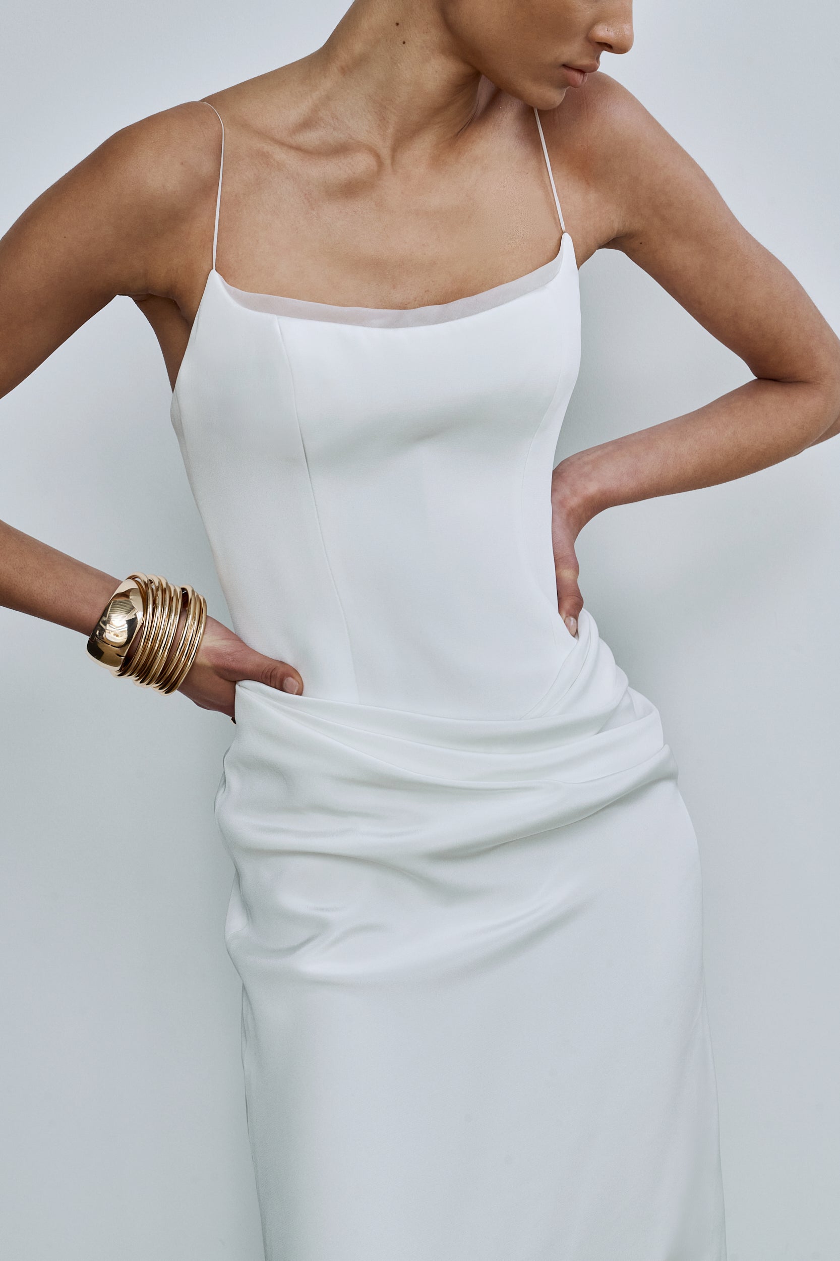 Close-up shot showing the drape detail on a white wedding gown with a curved neckline with an organza trim and slim straps