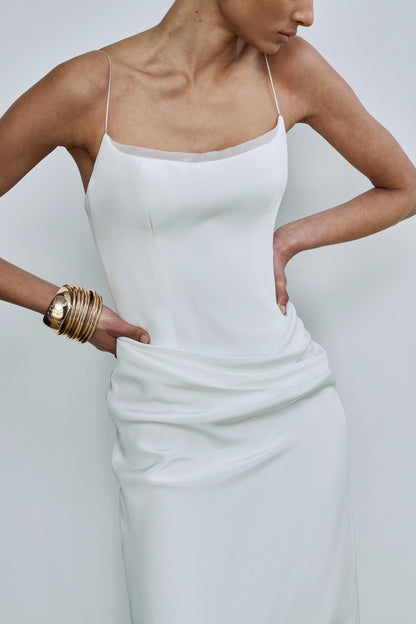 Close-up shot showing the drape detail on a white wedding gown with a curved neckline with an organza trim and slim straps