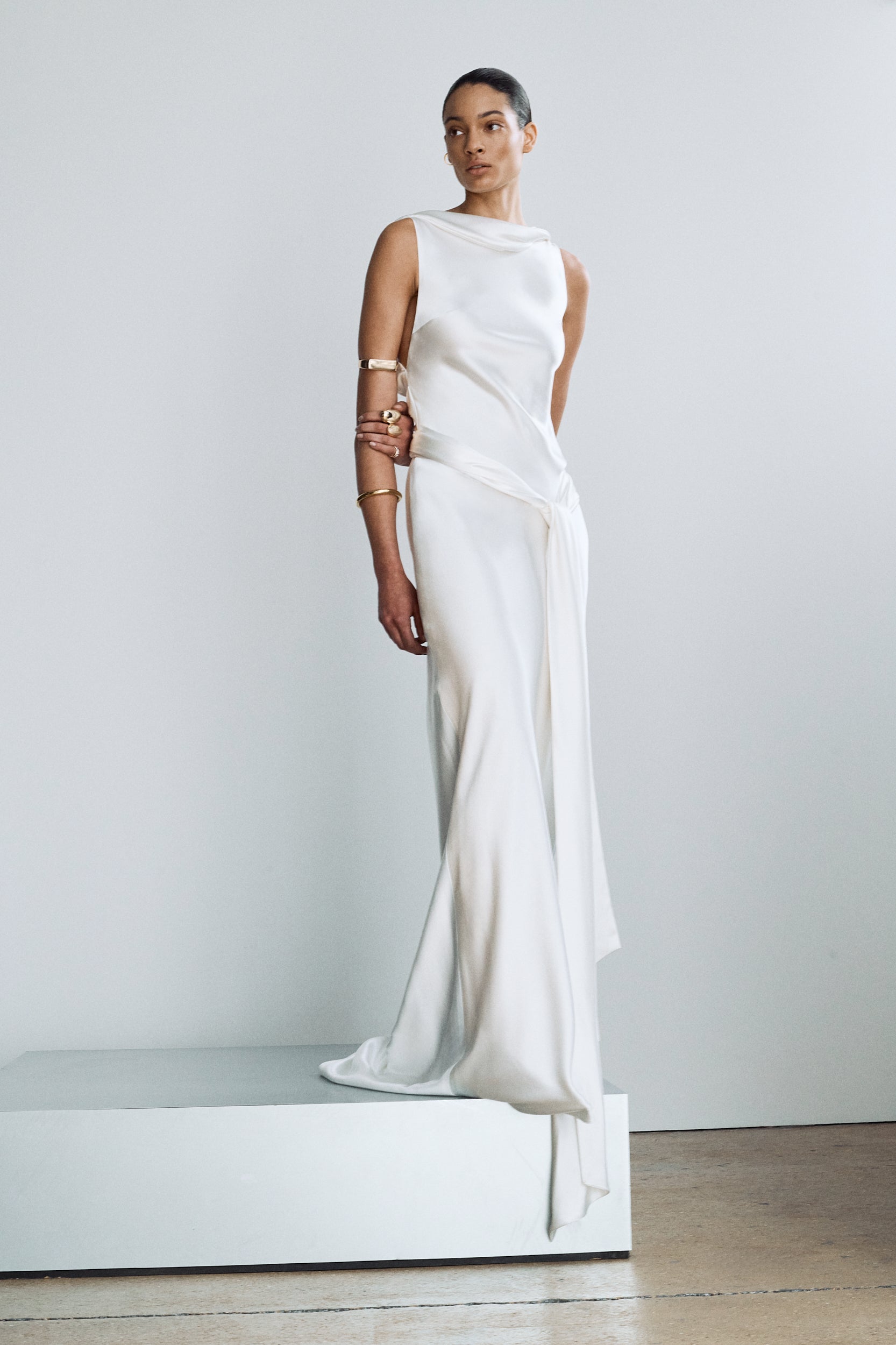 Front view of an elegant silk wedding gown, featuring a high neckline and sash ties styled at the hip