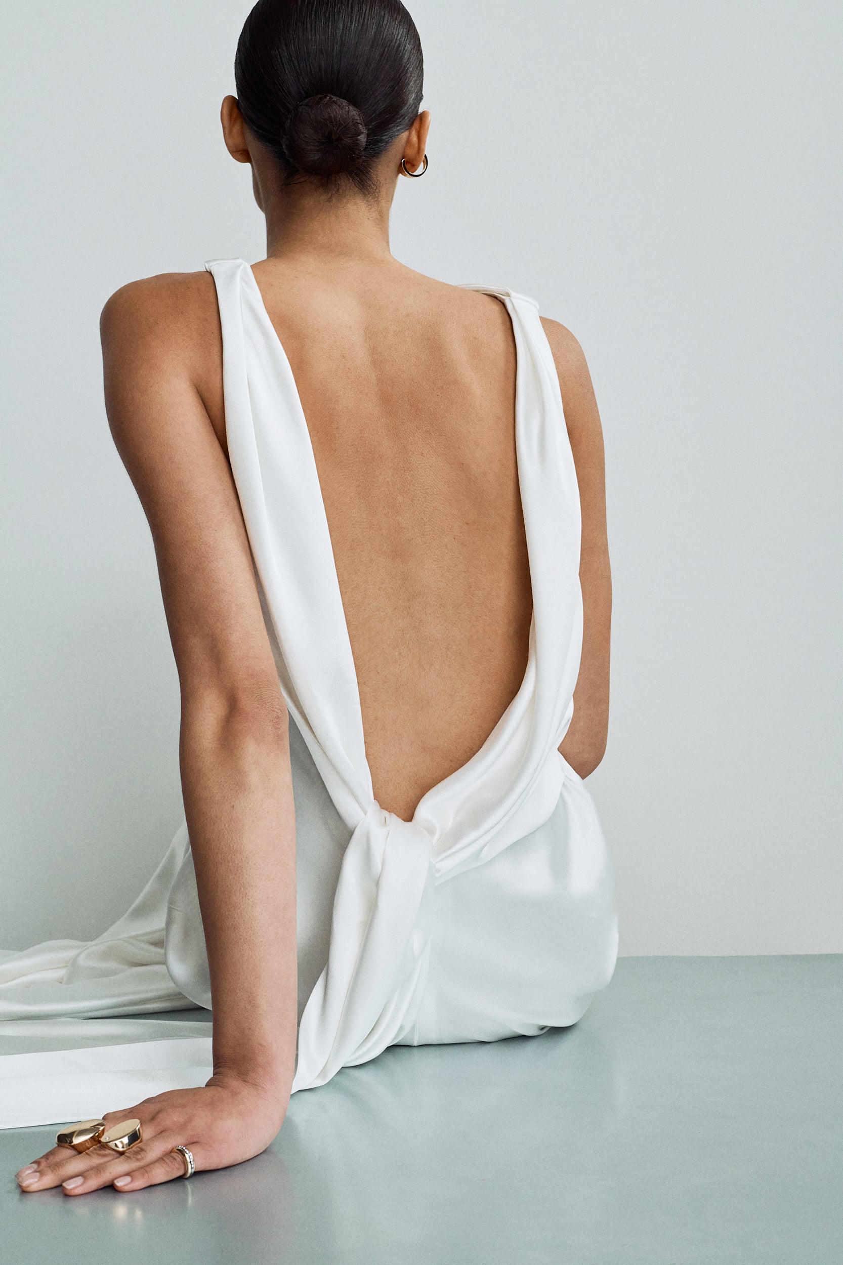 Close-up view showing a modern backless wedding gown, with draped detailing that ties at the waist