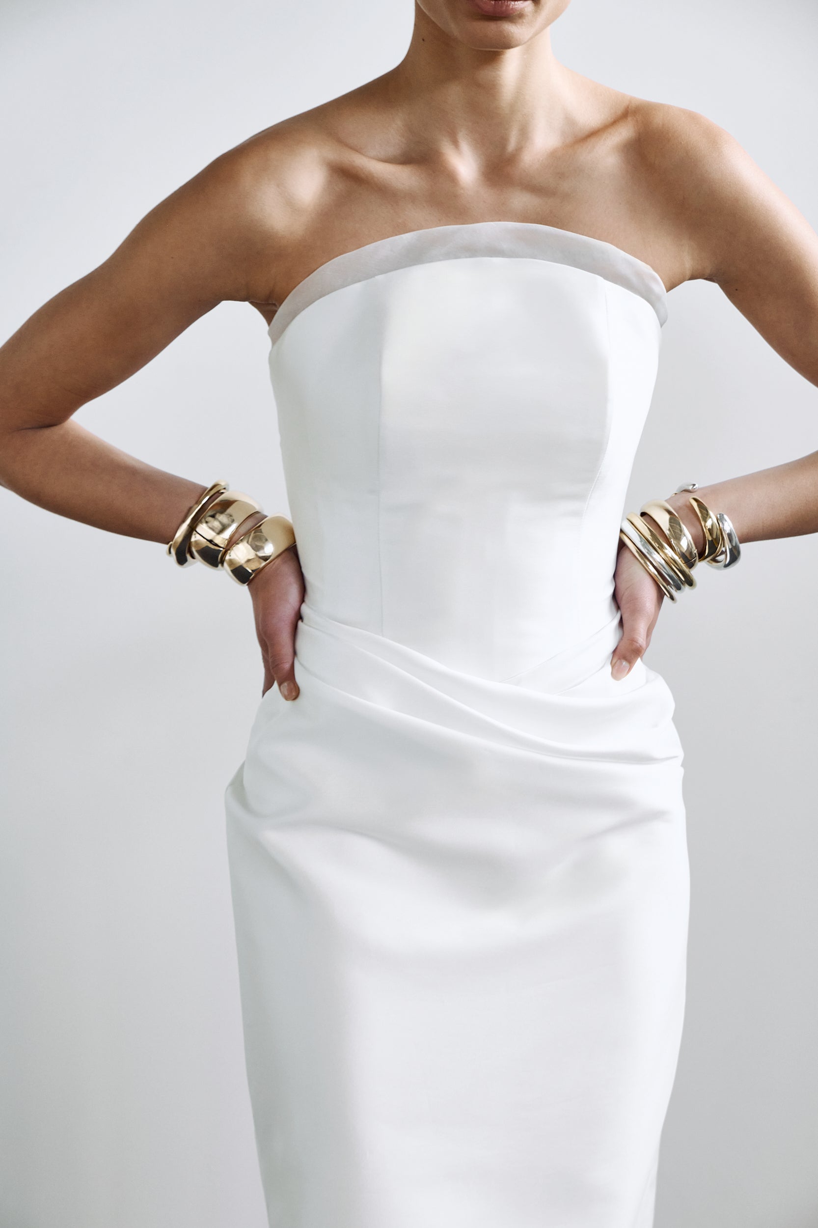 Sculpted crescent bridal gown with internal corset detailing and an elegant drape, styled with modern accessories