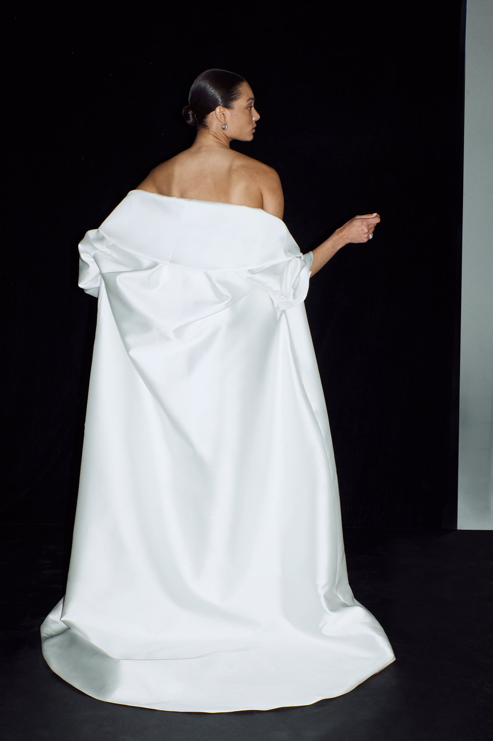 The back view showing an elegant opera cloak. Worn off the shoulder with an elegant flowing train.